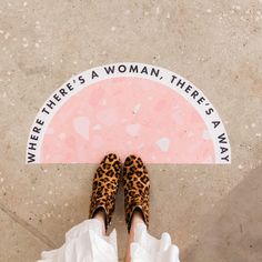 a woman wearing leopard print shoes standing in front of a pink and white sign that says, where there's a woman, there is a way