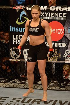 a woman standing on top of a wrestling ring in front of a man holding a punching glove