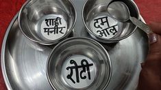 three metal bowls with spoons in them on a red tableclothed surface that says,