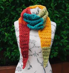 a multicolored crocheted scarf sitting on top of a mannequin