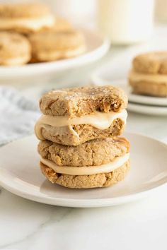 three cookies stacked on top of each other with frosting in the middle and two plates behind them