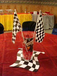 a red table topped with two checkered flags next to a glass filled with candy