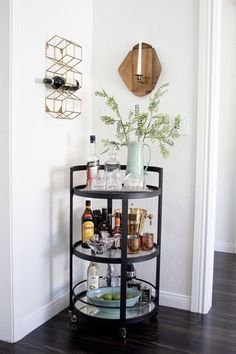 a round bar cart with drinks on it in the corner of a room next to a wall mounted clock