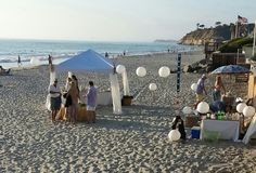 several people are on the beach with white balloons