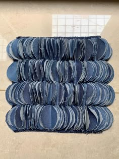 several stacks of folded blue jeans on a tile floor in front of a wall and window