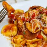 a white plate topped with pasta covered in sauce and cheese, next to a fork