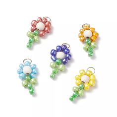 four different colored beaded flower charms on a white background with clippings attached to them