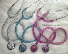 four different colored necklaces with silver and pink beads on them, one has a heart shaped pendant in the middle