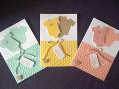 four cards with baby ones on them and tags hanging from the front, two are yellow, one is blue