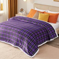 a purple and black plaid comforter set on a bed with orange throw pillows in the corner