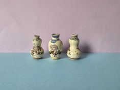 three small vases sitting next to each other on a blue and purple tablecloth