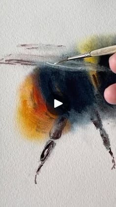 a person is drawing with colored pencils and watercolor paints on paper, using scissors