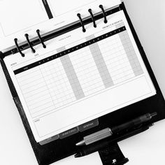 a black and white photo of a desk calendar on a clipboard next to a pen