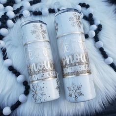 two white coffee mugs sitting on top of a black and white fur covered floor