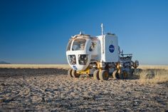 a vehicle that is sitting in the middle of some dirt and has wheels attached to it