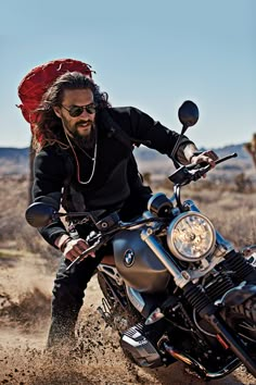 a man riding on the back of a motorcycle down a dirt road