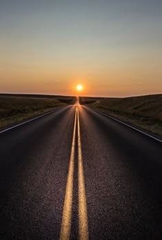 the sun is setting on an empty road with no cars or people in it,