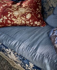 a blue couch with red and white pillows on it's back cushions are lined up against the wall