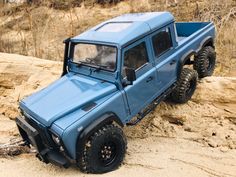 a blue toy truck driving on top of a sandy hill