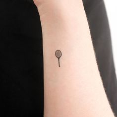 a woman's wrist with a small tattoo of a tennis racket on it