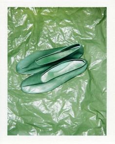 two pairs of green shoes laying on top of a plastic bag