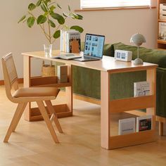 a laptop computer sitting on top of a wooden desk next to a green couch in a living room