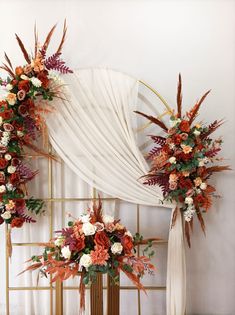 two tall floral arrangements in front of a white drape with orange and pink flowers