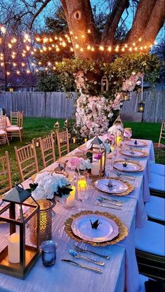 an outdoor dinner table set up with candles, plates and place settings for the guests