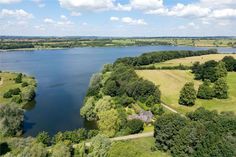 an aerial view of a large lake surrounded by trees and grass with houses on the other side