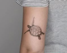 a woman's arm with a turtle tattoo on the left side of her arm