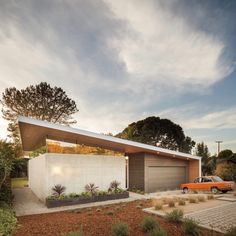 a modern house with an orange car parked in the driveway