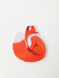 an orange and white brooch with a fox on it's back laying down