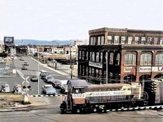 an old train is traveling down the tracks in front of some buildings and other cars