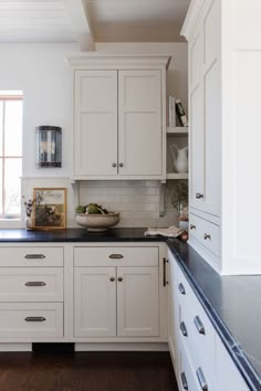 a kitchen with white cabinets and black counter tops