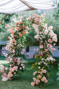 an outdoor wedding ceremony with flowers on the arch