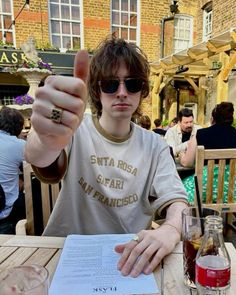 a man sitting at a table with a menu in front of him and pointing to the camera