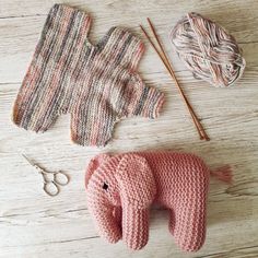 an elephant made out of knitted material next to knitting needles and yarns on a wooden surface