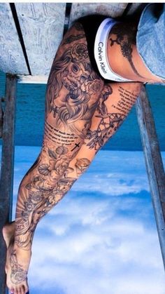 a man with tattoos on his legs and leggings is standing on a ladder