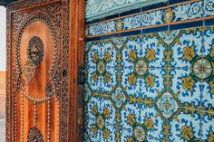 an ornate wooden door with blue and green tiles on it's sides in the desert