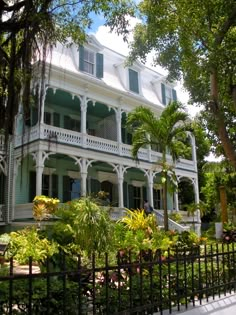 a large white house surrounded by trees and plants