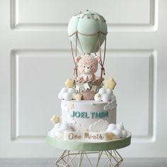 a birthday cake with a teddy bear in a hot air balloon topper on it