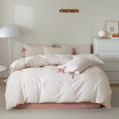 a bed with white sheets and pink polka doted pillows on top of it in a bedroom