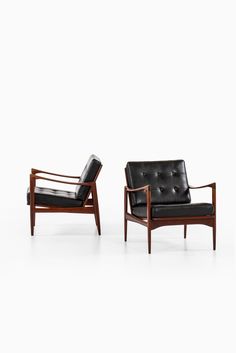 two black leather chairs sitting next to each other on a white surface with no one in it