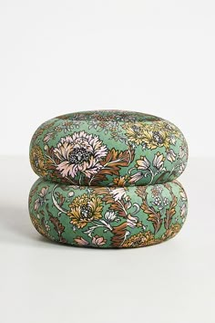 two round cushions with flowers on them sitting side by side in front of a white background