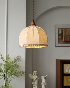 a lamp hanging from a ceiling in a living room next to a vase with flowers