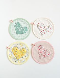 four embroidered heart coasters are shown on a white surface