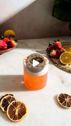 an orange juice in a glass next to sliced strawberries and lemons