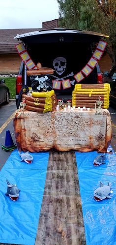 the trunk of a van is covered with blue tarps and pirate decorations, along with other items