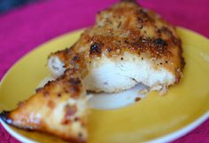 a piece of chicken on a yellow and white plate with pink table cloth in the background