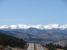 a highway with mountains in the background and cars driving down one lane on both sides